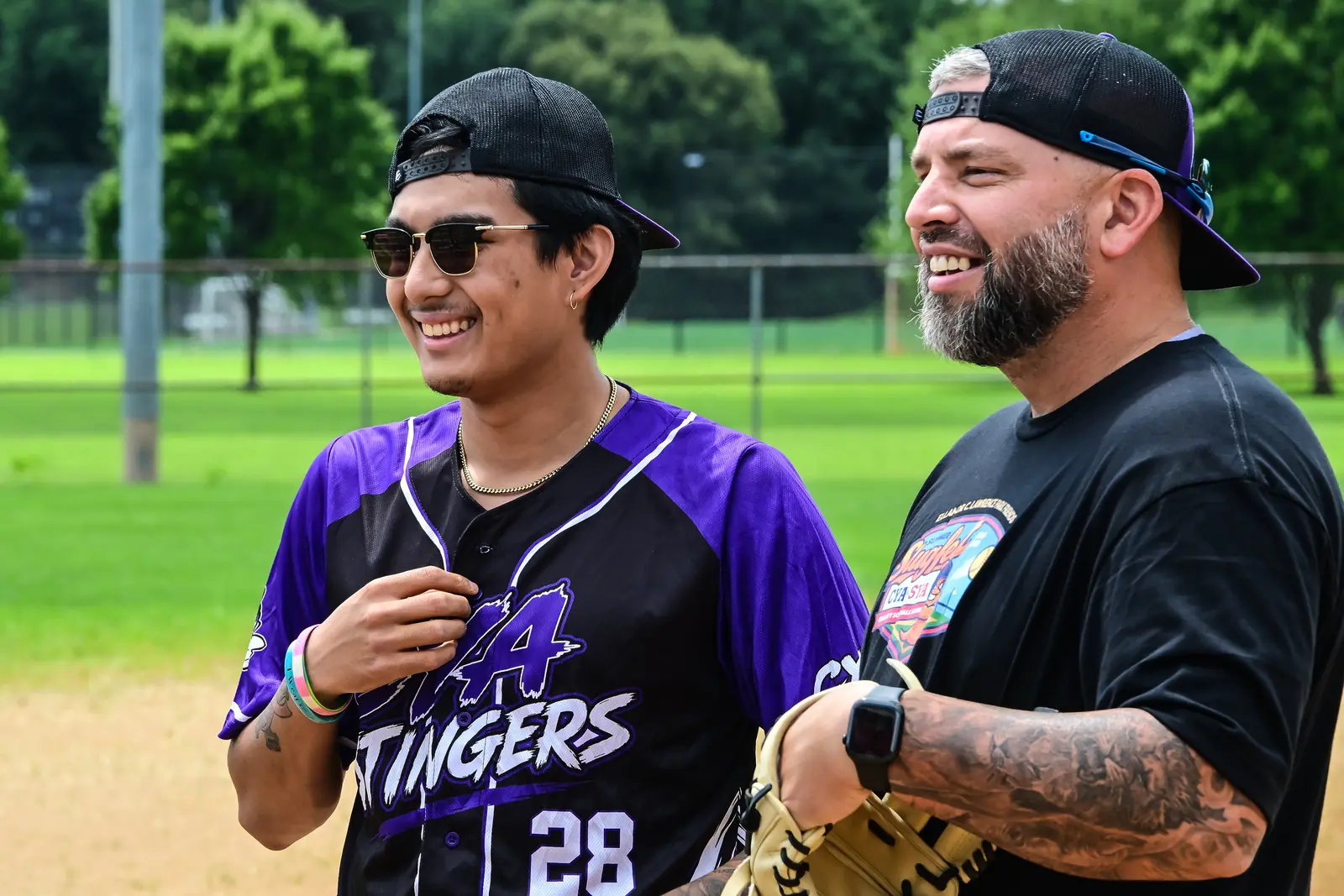 Two Summer Slugfest softball players smiling together, including one in a purple CYA Stingers jersey.