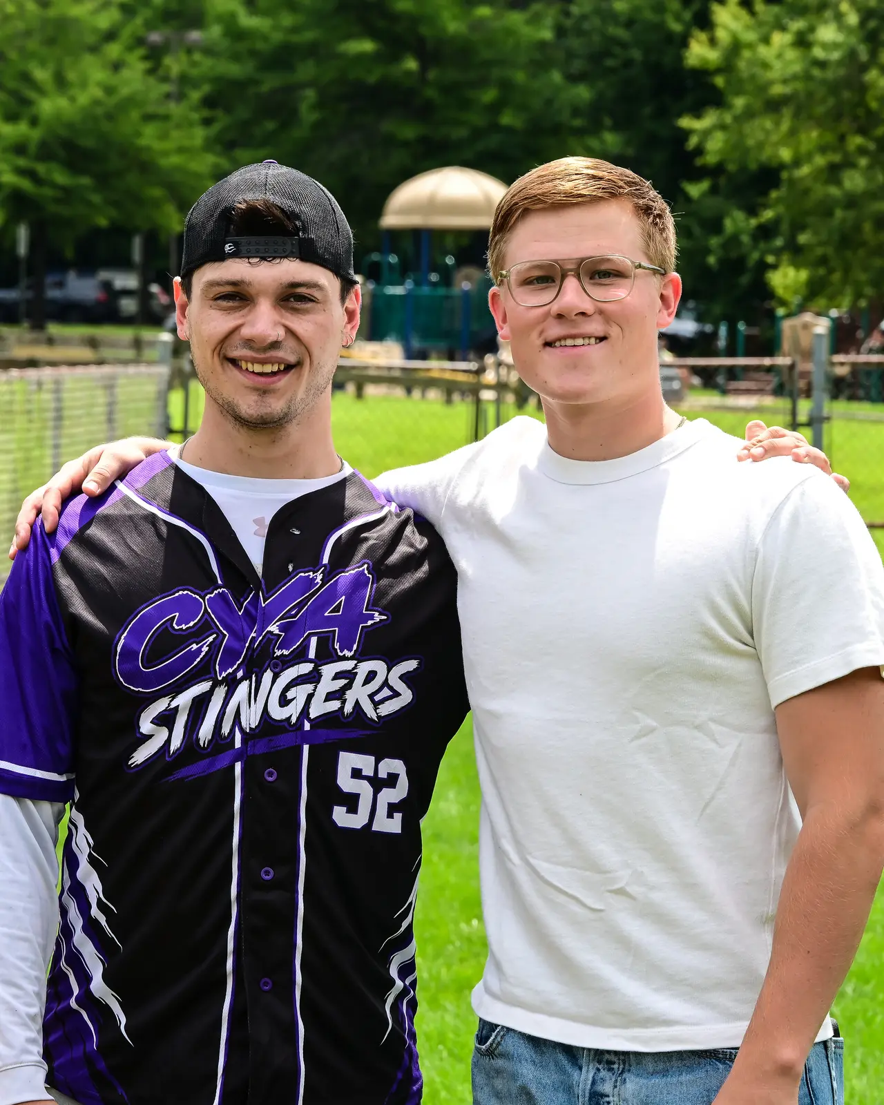CYA Stingers softball player and a community supporter posing together beside the field.