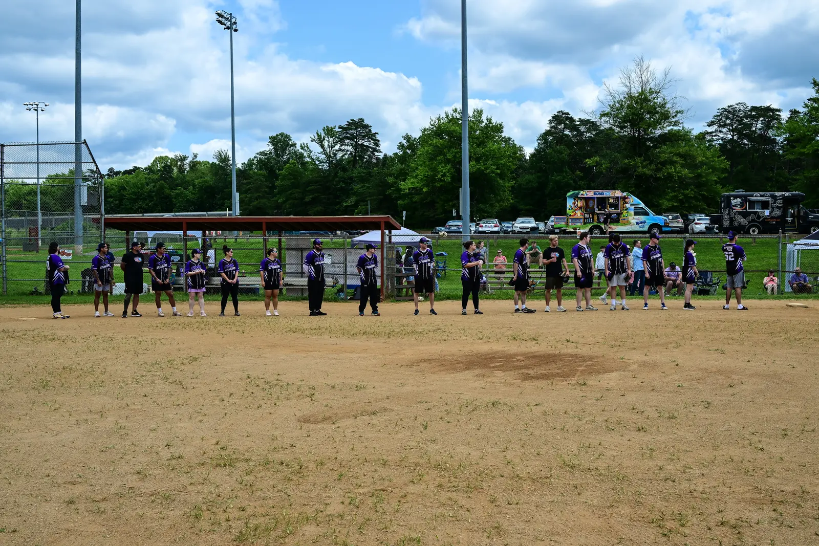 CYA softball players in purple jerseys lined up across the Summer Slugfest field.