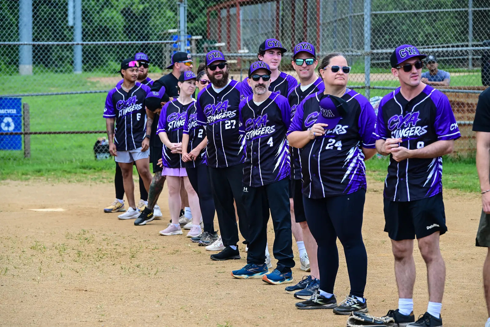 CYA Stingers softball players standing shoulder to shoulder in purple uniforms.