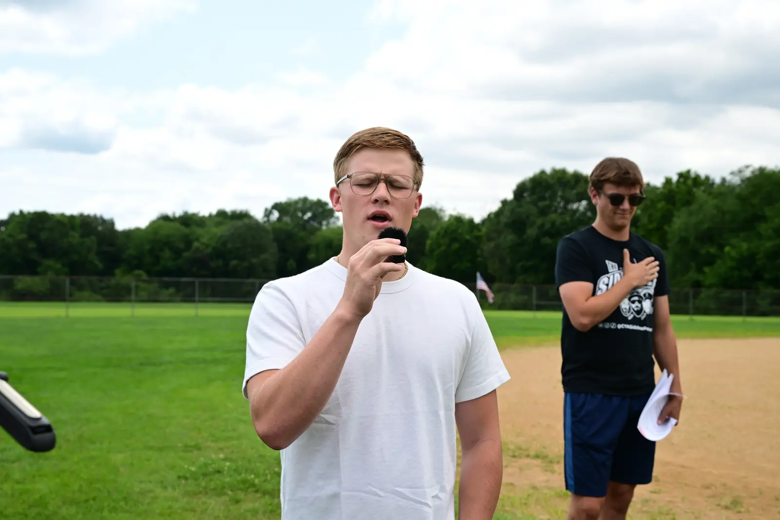 Field announcer speaking into a microphone with another event organizer standing behind him.