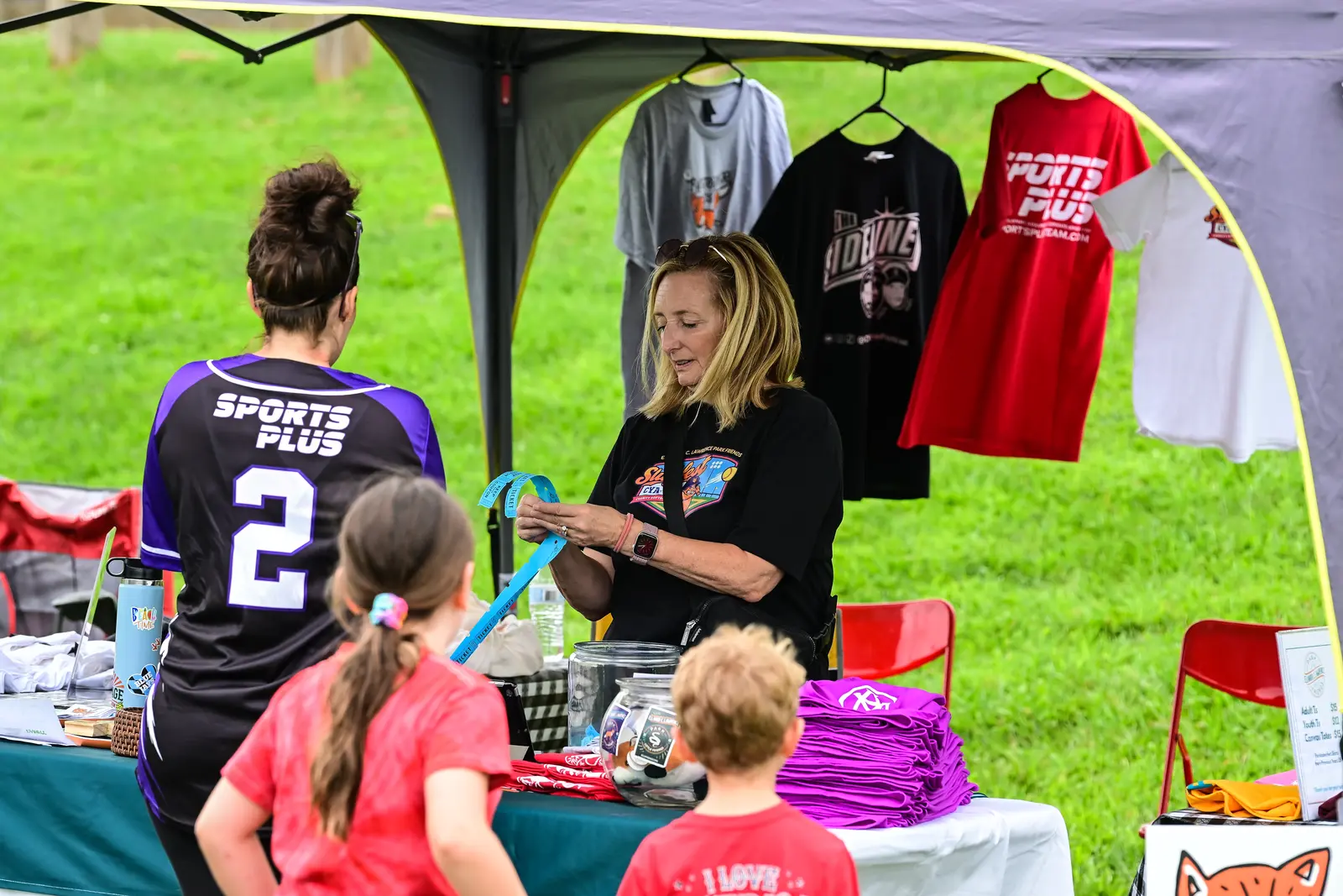 Volunteer helping visitors at the Summer Slugfest charity merchandise tent.