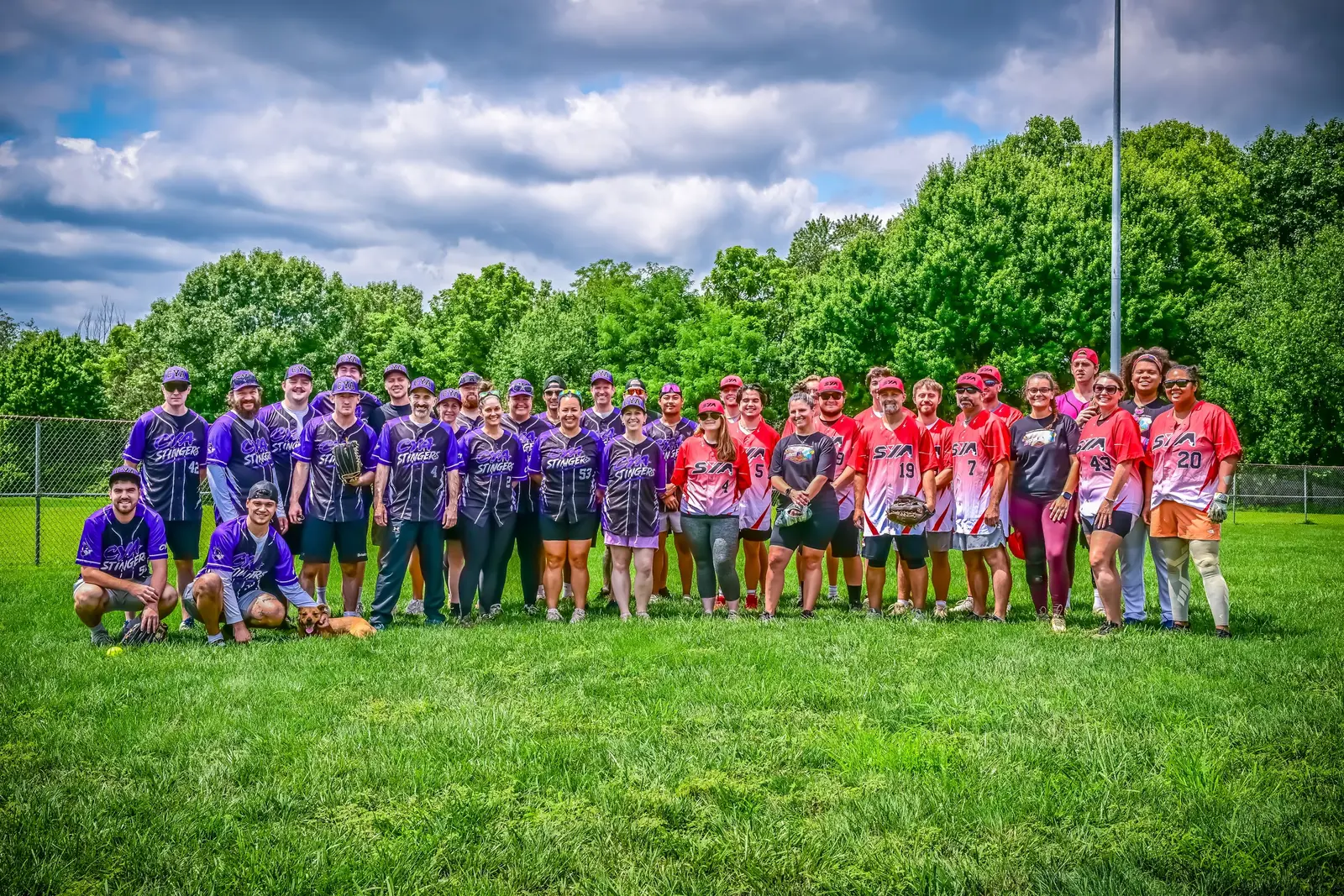 CYA and SYA softball teams posing together in purple and red uniforms on the grass.